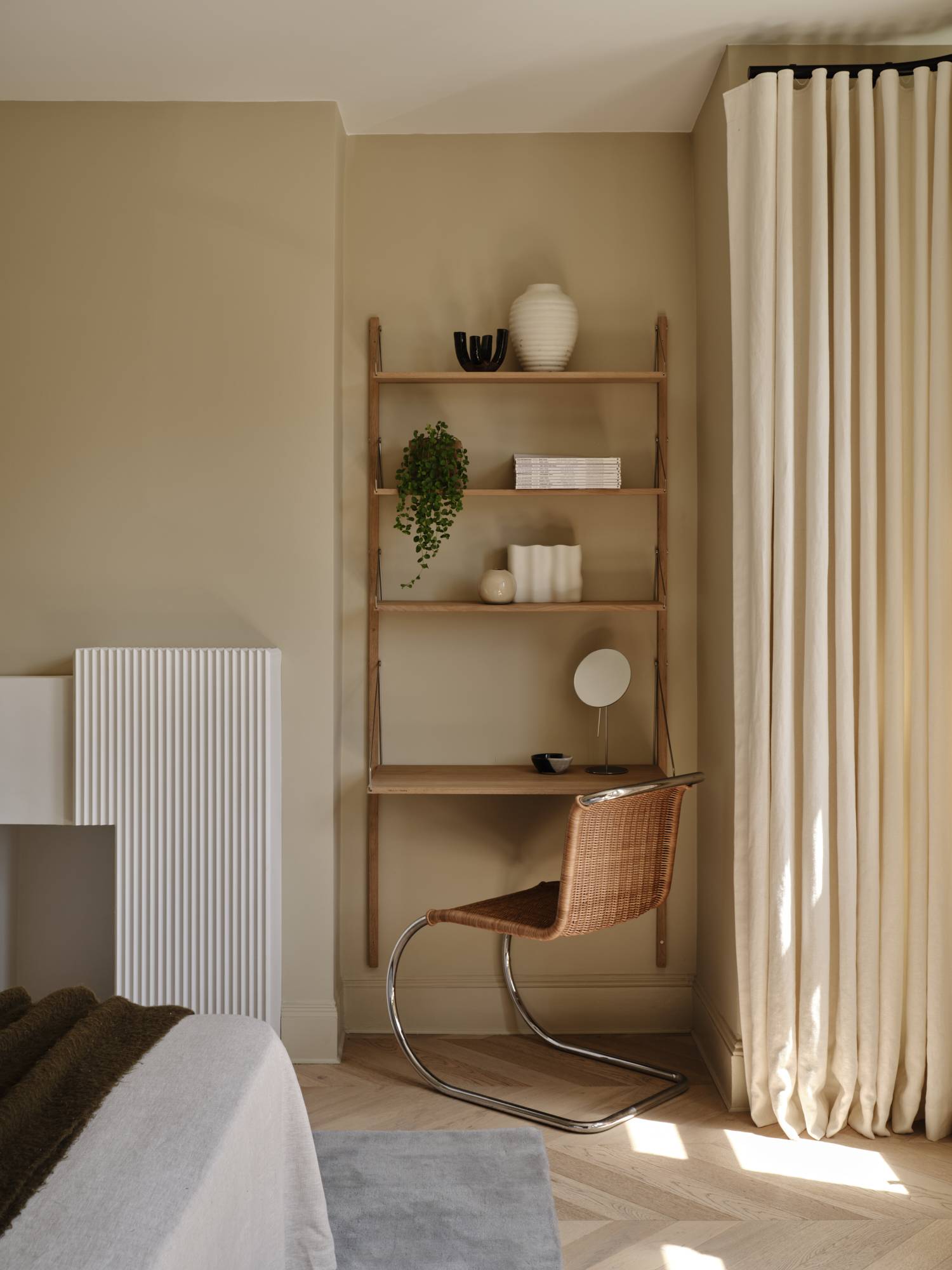 Love Locations boutique hotel style bedroom Lewisham SE23: Bedroom corner highlighting a sleek integrated oak ladder desk unit and a mid-century leather chair backdrop.