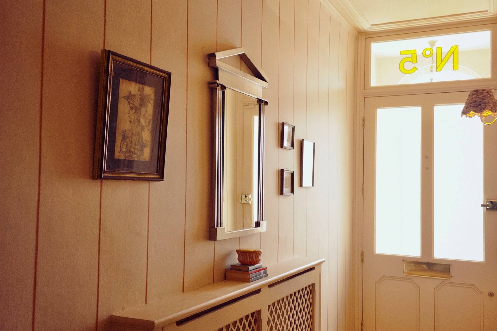 Traditional hallway corridor view featuring cream vertical wall panelling, a radiator cover, and a framed art print, Love Locations Hounslow.