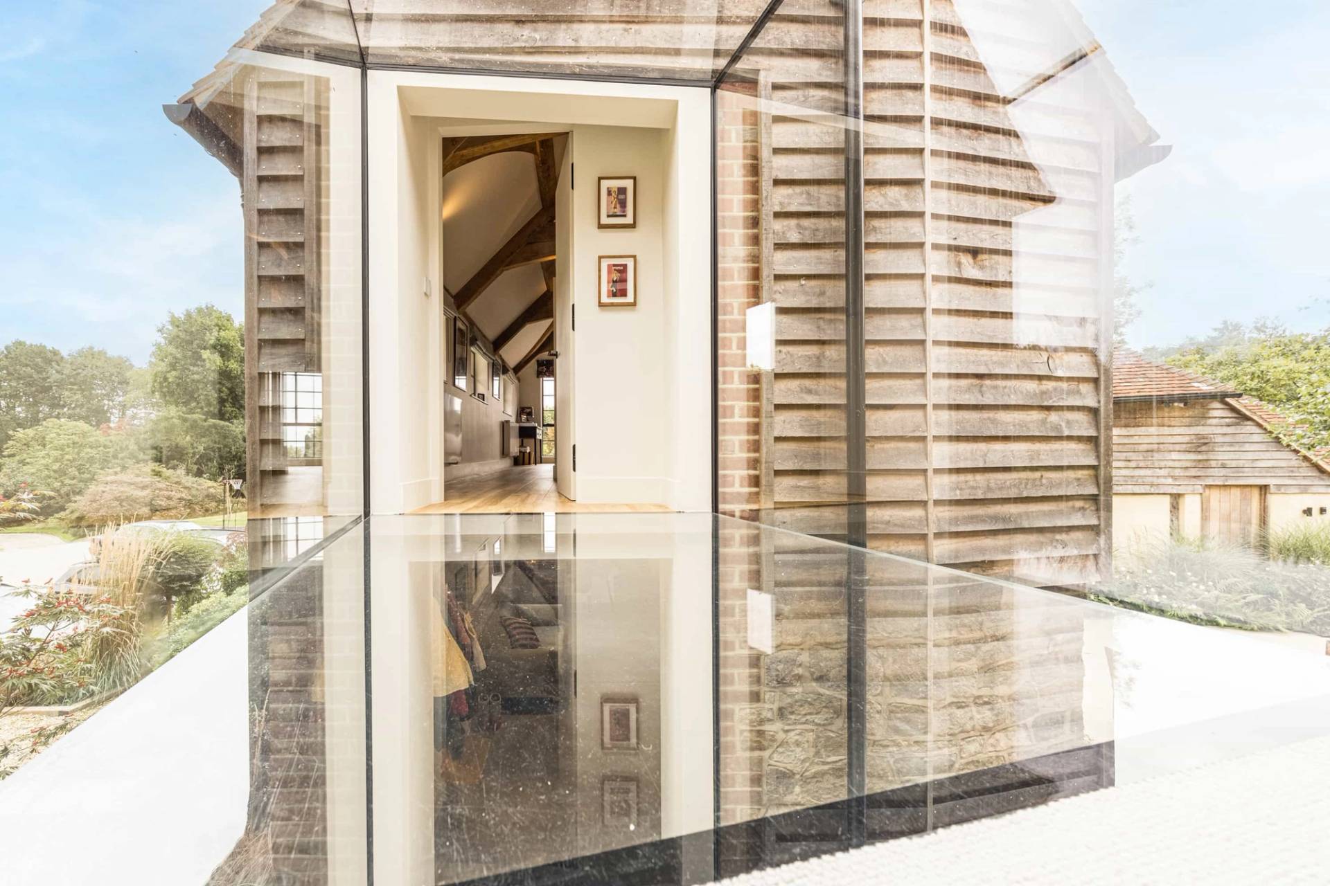 Contemporary glass link walkway featuring a clear glass floor section and stone walls, Love Locations GU28.