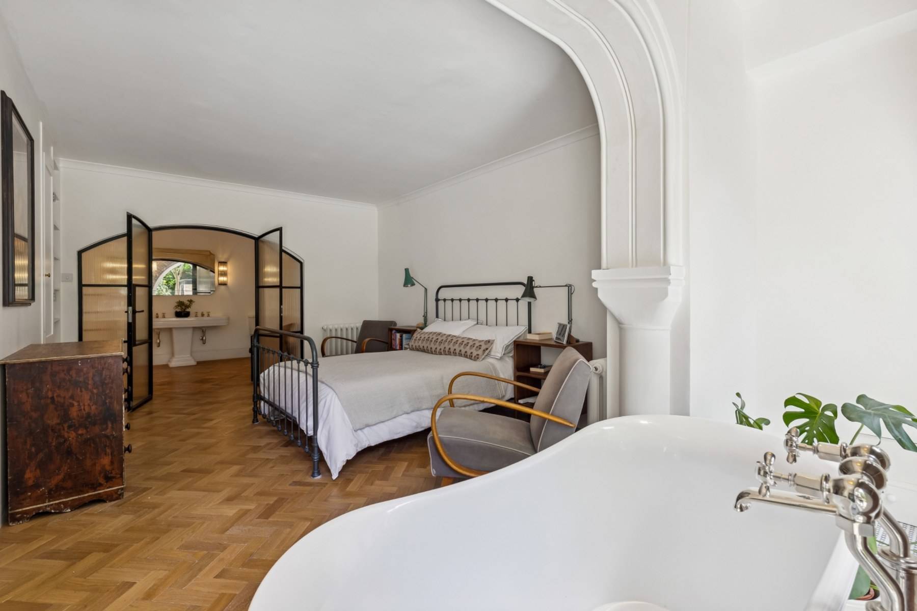 Bedroom shoot location with iron bed and arched view to an ensuite in Hampstead NW3 via Love Locations.