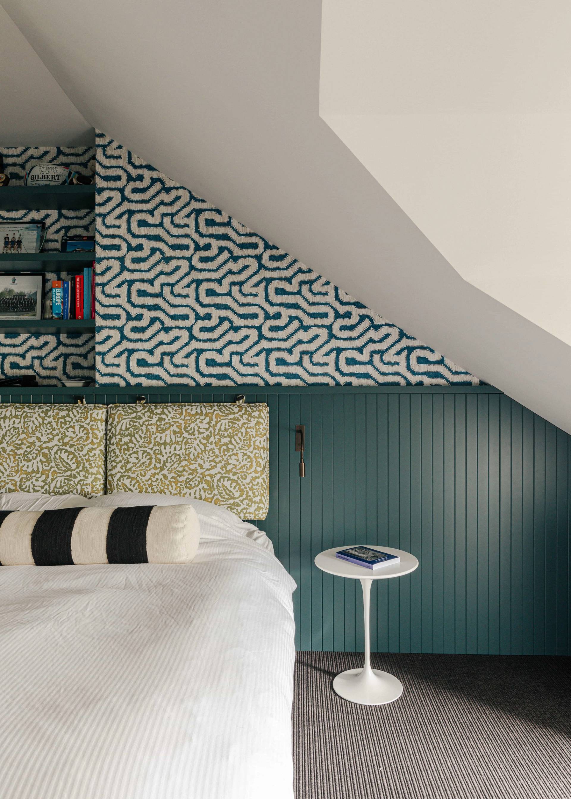 Attic bedroom featuring a teal slatted wall headboard and teal patterned wallpaper, ideal for cozy lifestyle filming, Love Locations SW13.