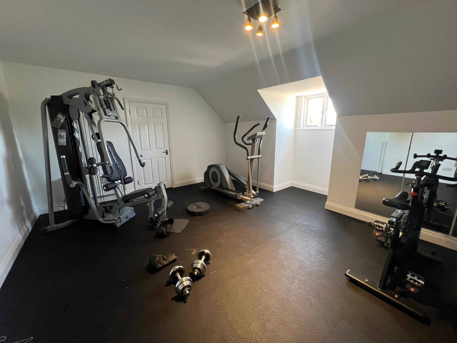Private home gym setup featuring commercial multi-gym weights, cardio machines, and black rubber flooring, Love Locations BR7.