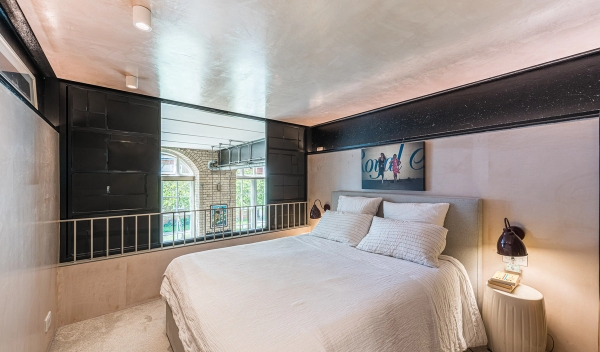 Mezzanine loft bedroom location space with a double bed looking over a safety railing onto the main living room, Love Locations.