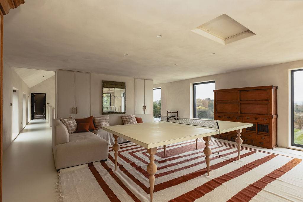 Spacious entertainment room with a ping pong table, corner sofa, and views across Hampshire countryside, Love Locations GU32.