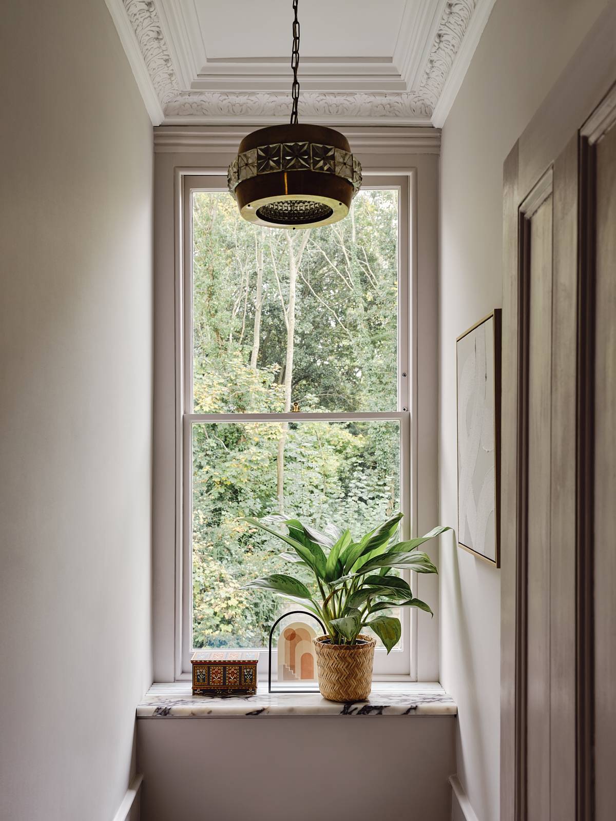 Sash window view framing lush green trees set in a plaster pink bathroom, Love Locations CR0.