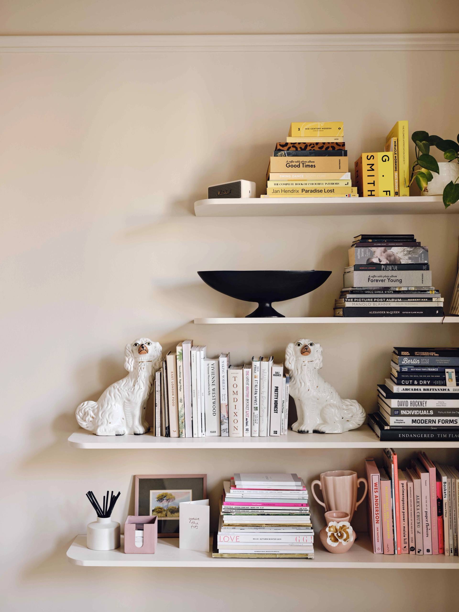 Open white shelving units styled with books and white ceramic dog figurines set against neutral walls, Love Locations CR0.
