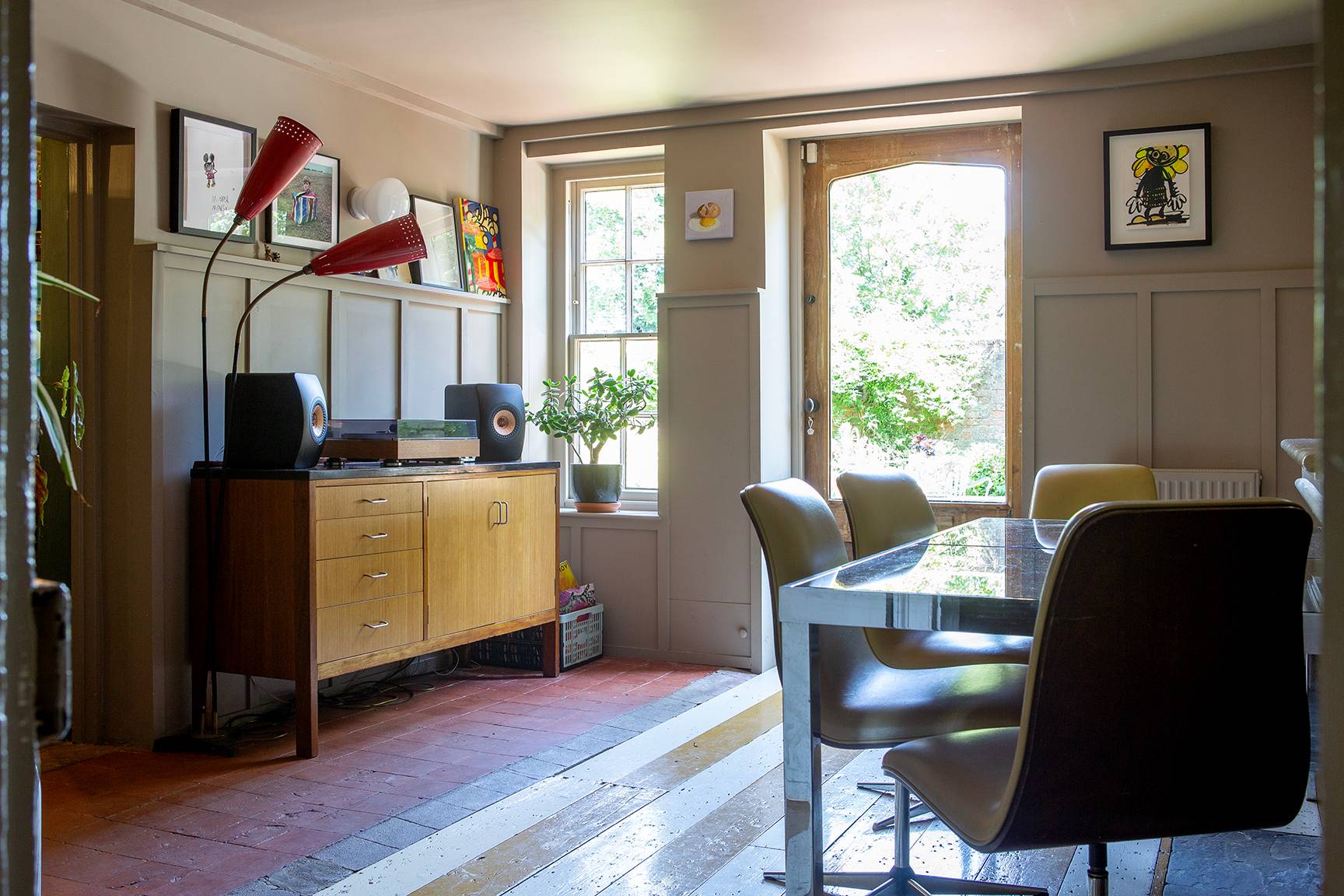 Retro dining setup featuring a wooden sideboard, red lamps, glass table, and garden view patio doors, Love Locations ME13.