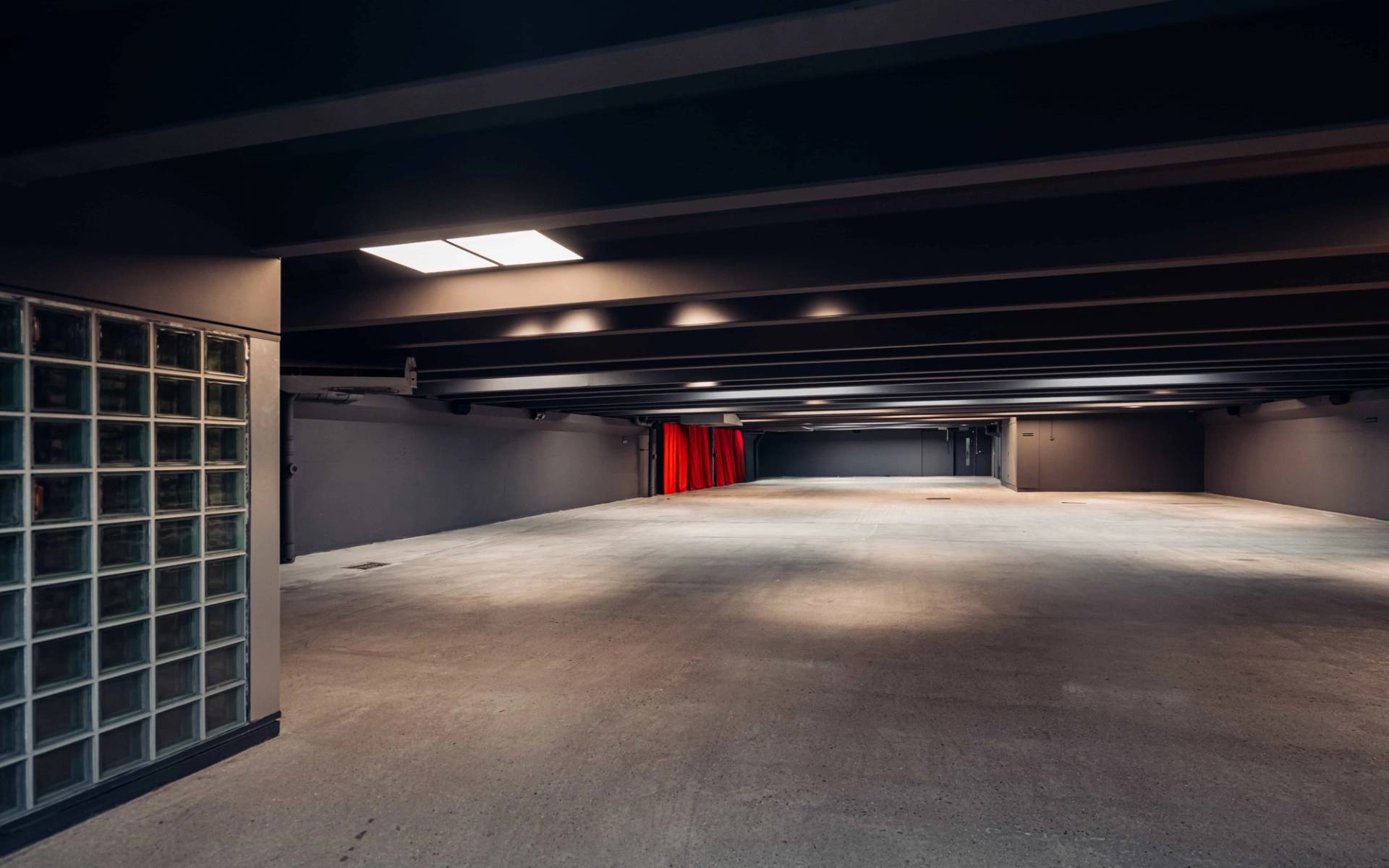 Vast open-plan underground vault location for commercial video shoots in Brentford TW8 via Love Locations, framed by dark ceiling beams and red drapery.