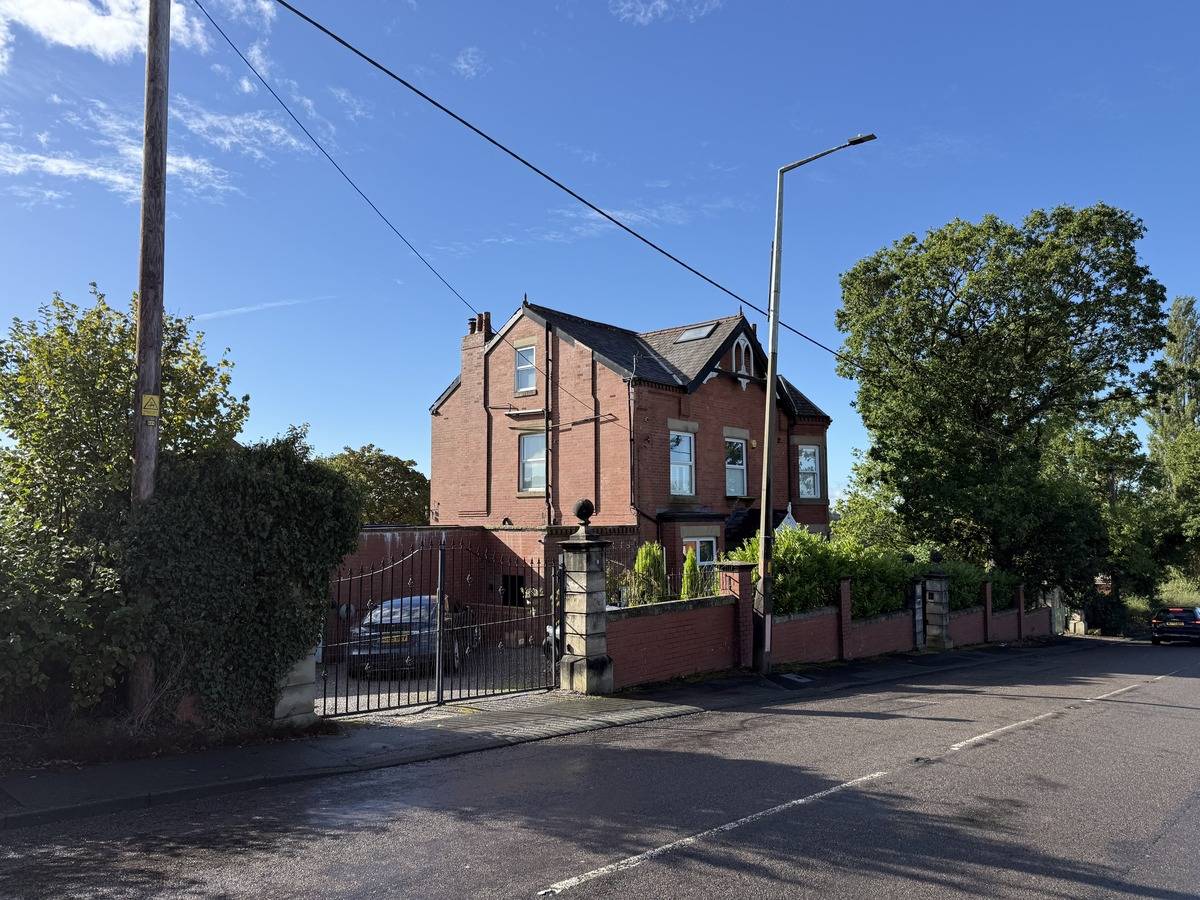 Street-level front elevation view of the three-story red brick detached family home film location in Stockport SK6 from Love Locations.