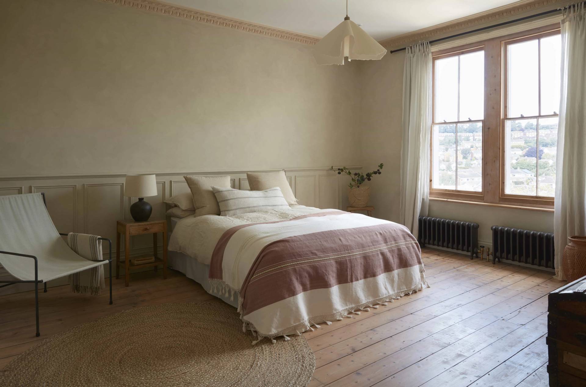 Cozy attic bedroom with a sloped ceiling, striped bed linens, and wooden floorboards, perfect for sleepwear and mattress lookbooks, Love Locations.