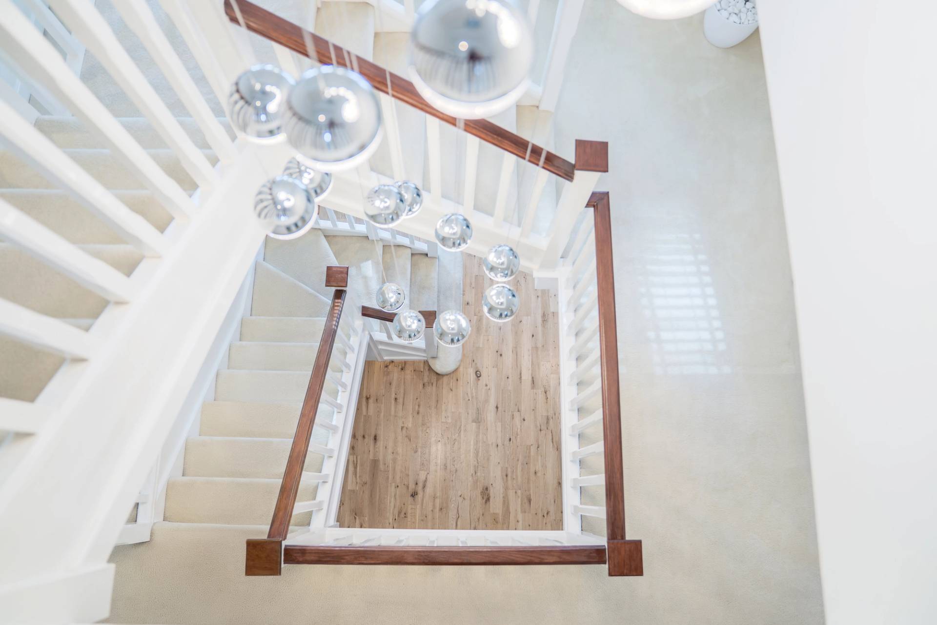 Top-down view of a double-height entrance hall staircase and light wood flooring, Love Locations RM11.