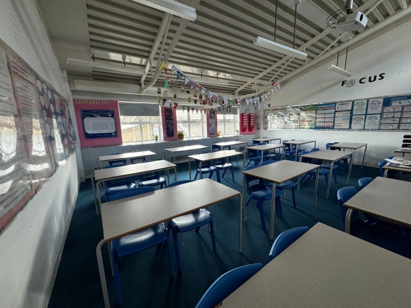 Love Locations contemporary secondary school classroom Cockfosters EN4: Standard educational learning room with clean white desks and deep blue carpeting, ideal for classroom film scenes.