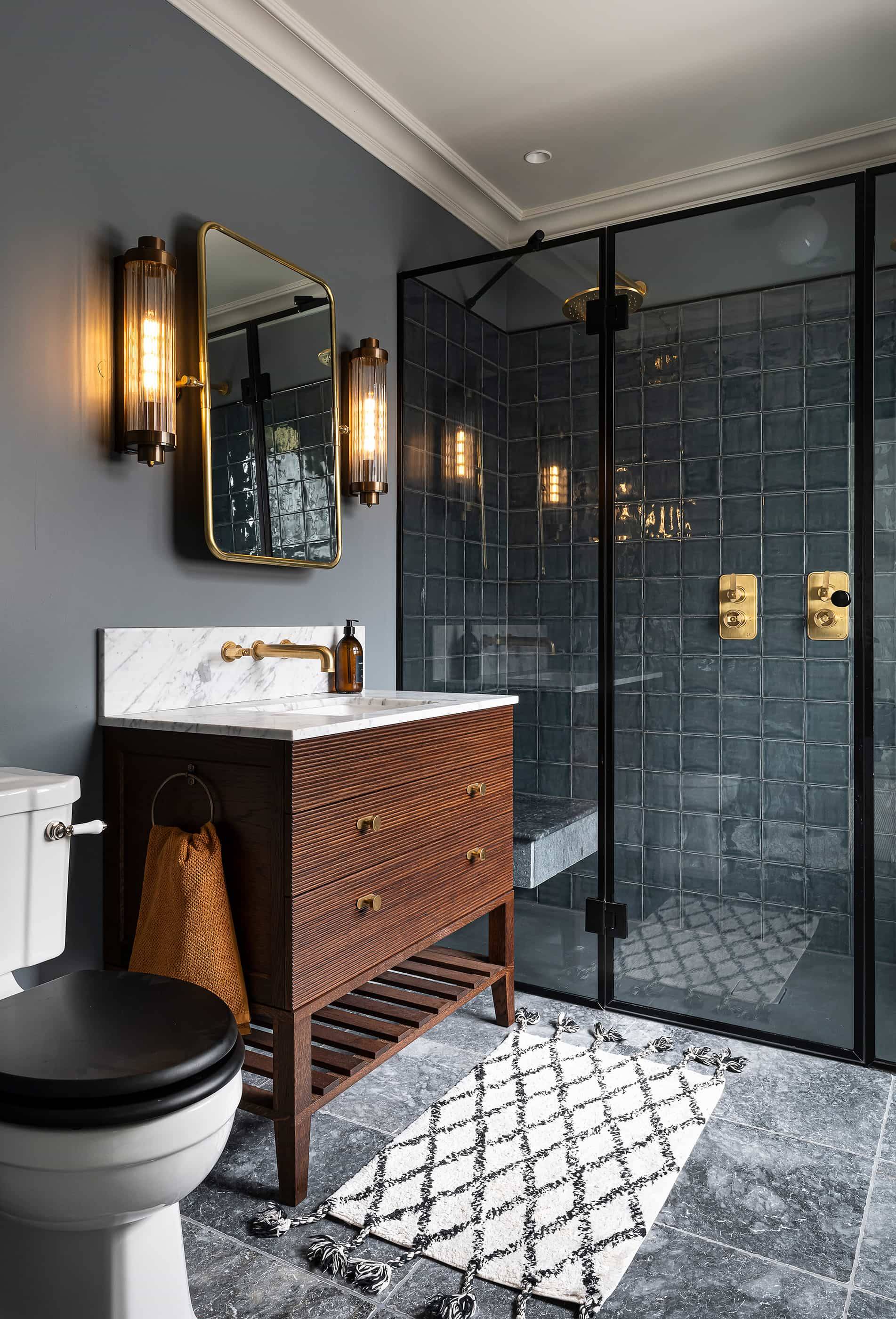 Luxury bathroom suite with a dark wood vanity, black frame shower enclosure, and brass fixtures, Love Locations.