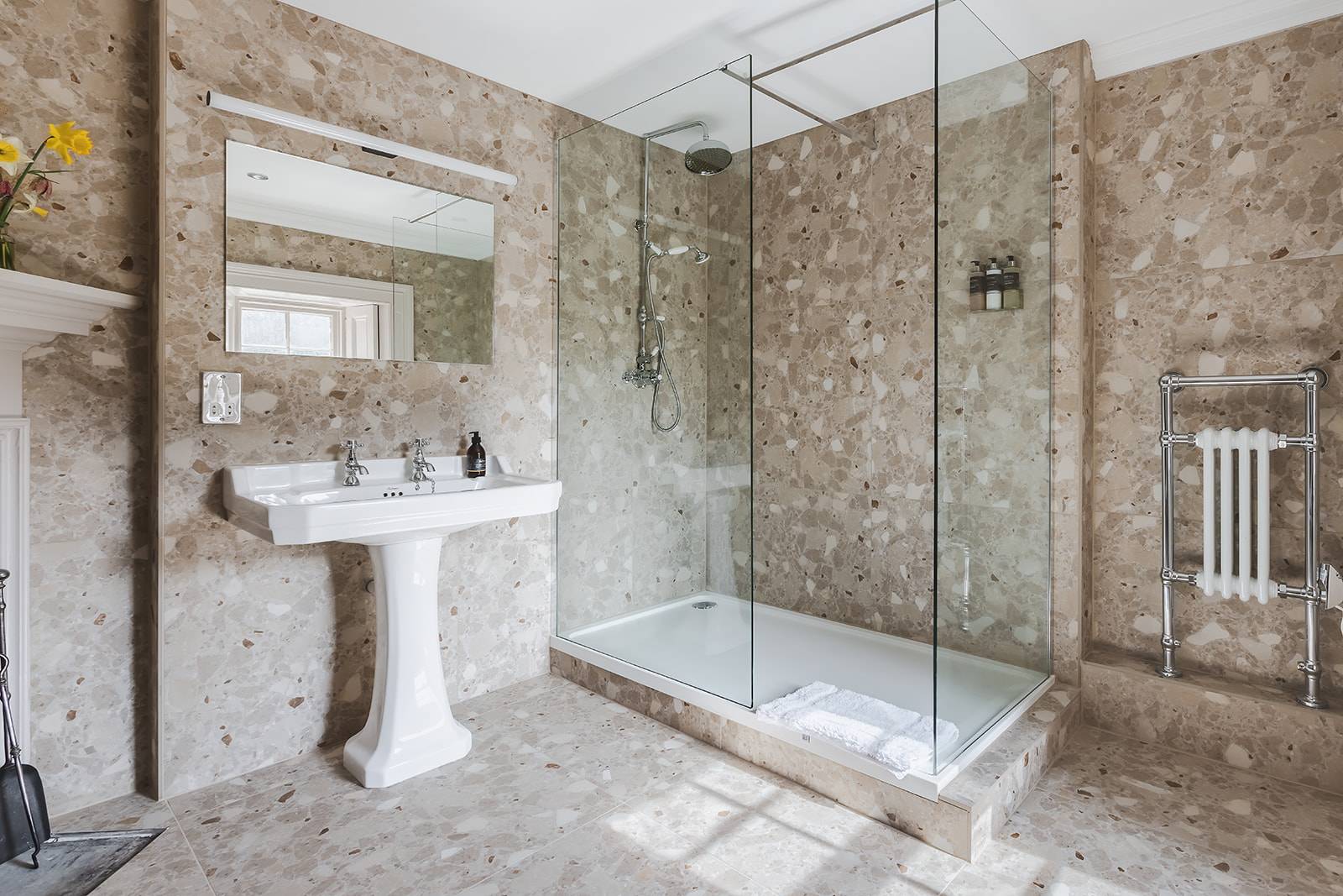 En-suite shower room featuring stone-effect wall tiles and a white pedestal sink, Love Locations KY15.
