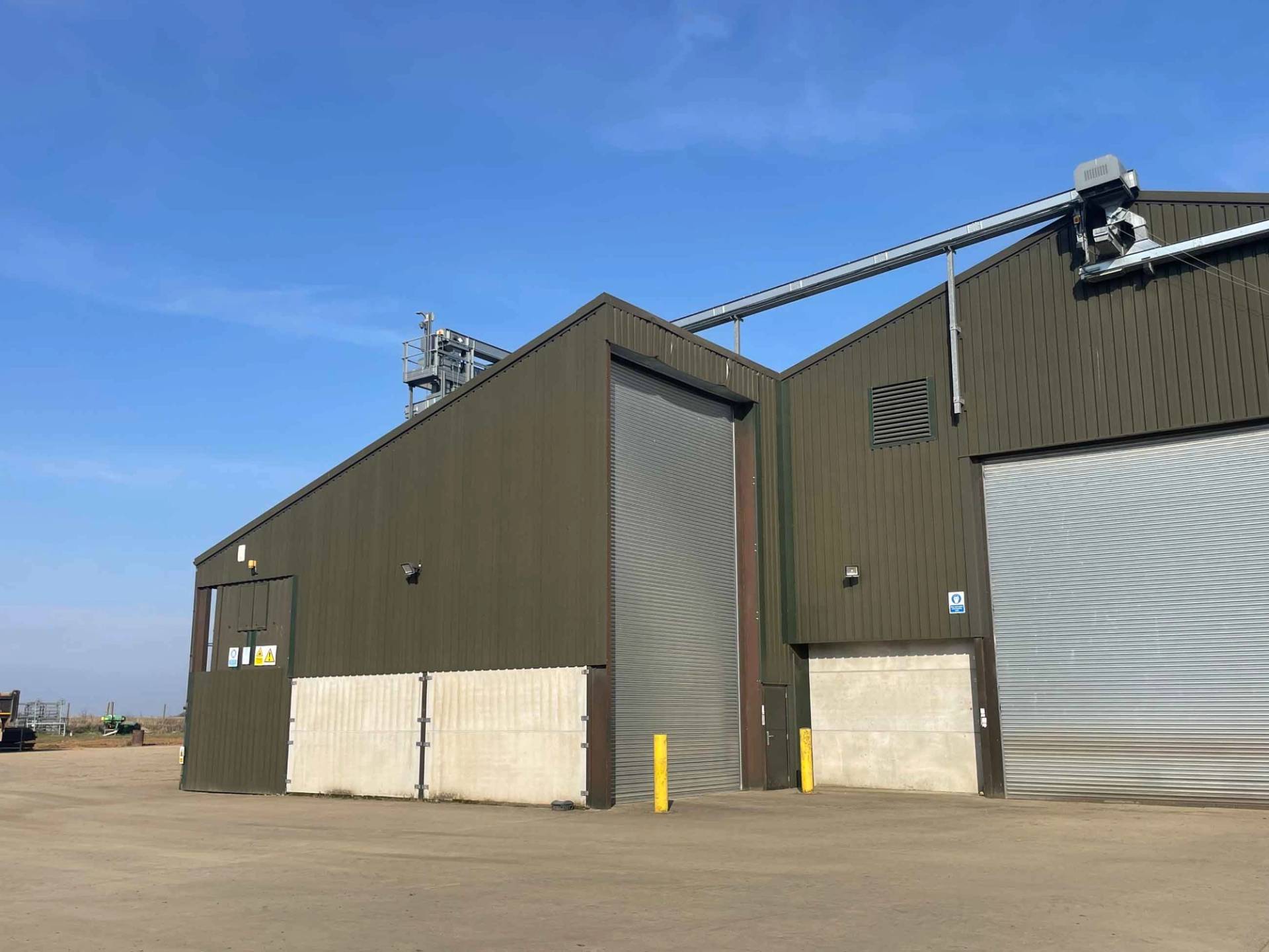 Large steel-framed agricultural warehouse with concrete base panels, ideal for production unit storage and crew parking bases, Love Locations.