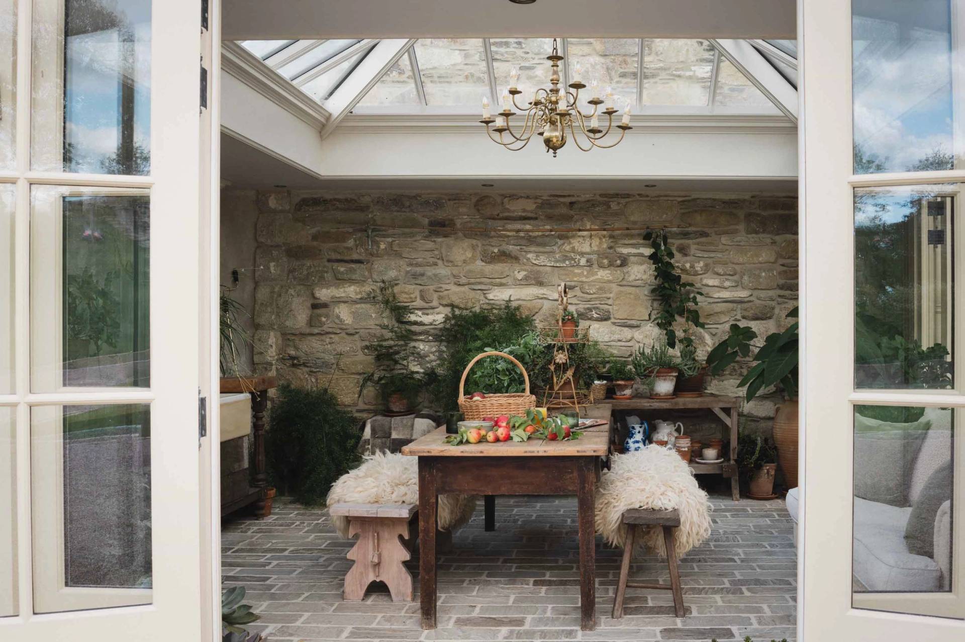 Glass-roof conservatory and orangery shoot location with exposed stone walls and wooden dining table in Newquay through Love Locations.