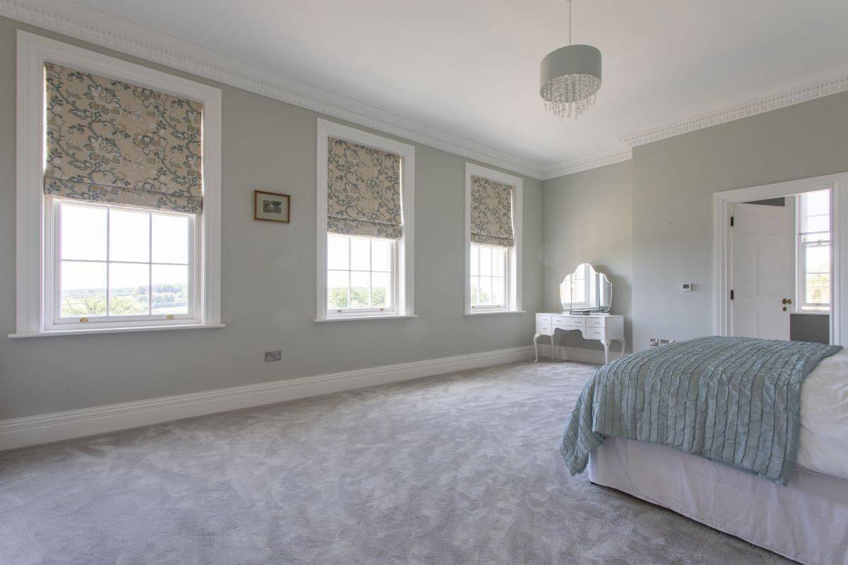 Three large Georgian sash windows flooding a pastel blue bedroom with natural light, perfect for daylight filming via Love Locations.