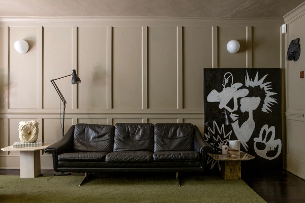 Eclectic period house location in Faversham, ME13 featuring grey wall panelling, black leather sofa, and green carpet via Love Locations.