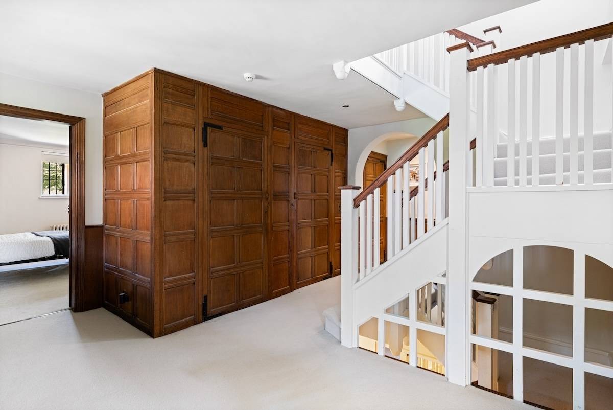 Built-in antique wooden storage cabinets set beside a traditional white staircase, Love Locations RH13.