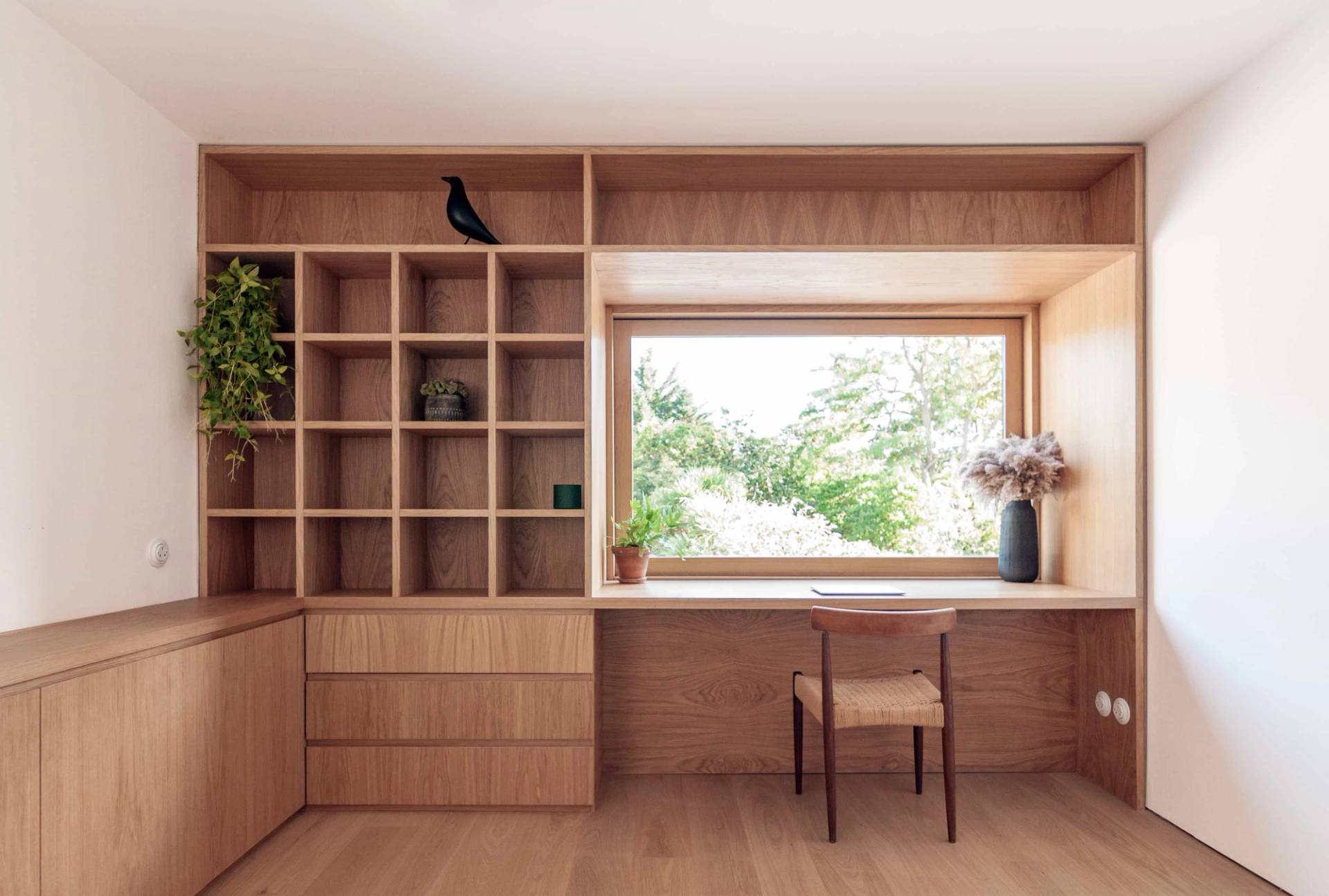 Bespoke floor-to-ceiling wooden bookcase and study area in Hackney N16 by Love Locations, with integrated desk seating and a garden view window.