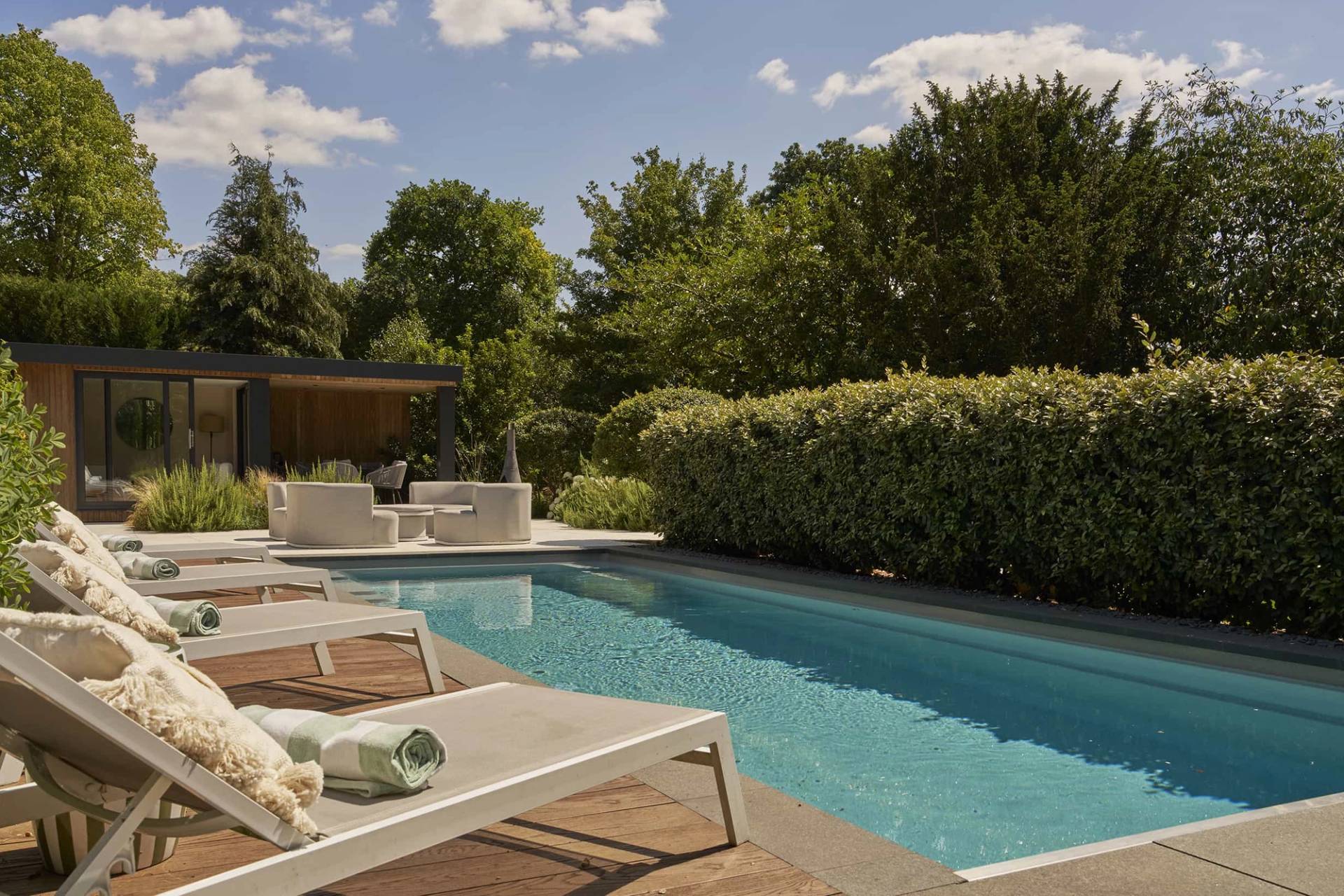 High-end residential swimming pool area surrounded by manicured privacy hedges, available through Love Locations.