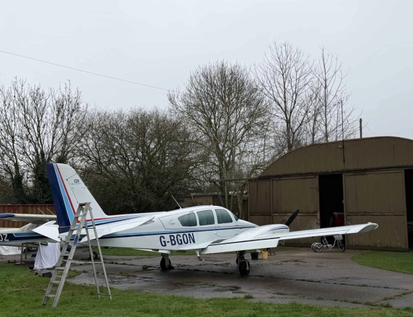 Close-up of a vintage twin-propeller aircraft parked outside a rural airfield hangar, perfect for aviation historical drama shoots, Love Locations.