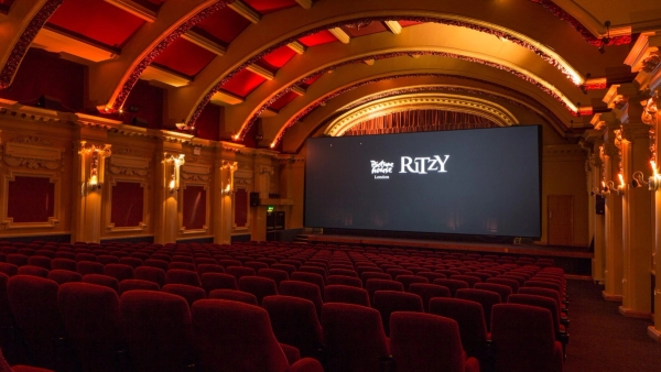 Side perspective shot of the classic red velvet seating and illuminated cinema screen at The Ritzy Screen 1 production space in Brixton SW2 through Love Locations.