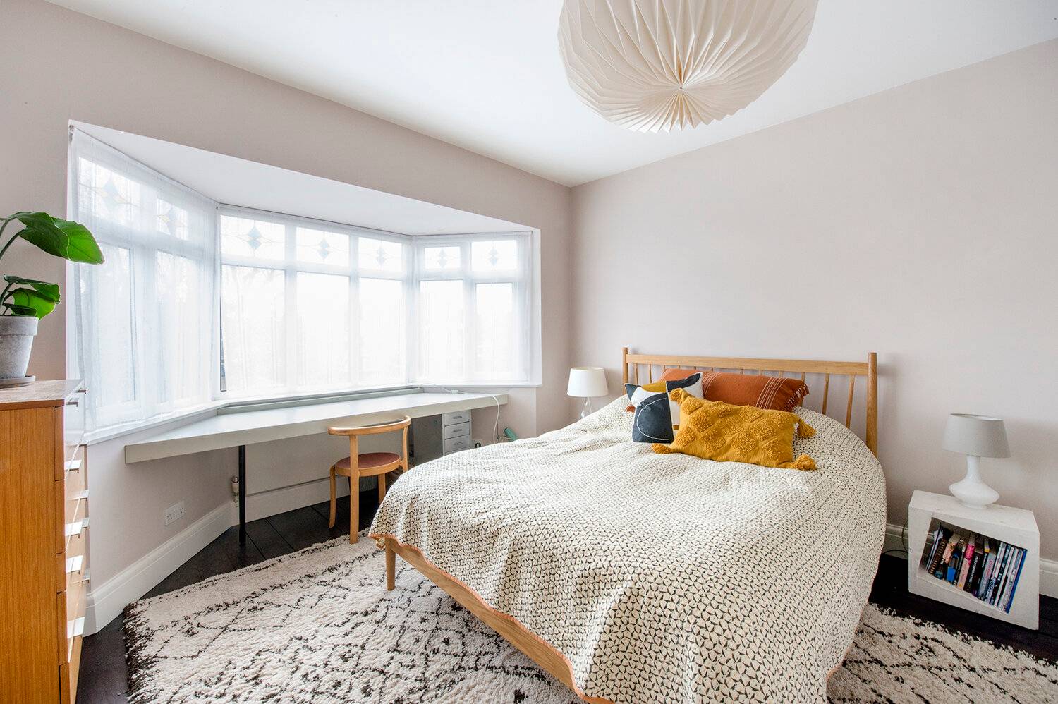 Bright master bedroom in Forest Hill, SE23 featuring a beige bedspread, Berber area rug, bay window, and wooden desk nook, Love Locations.