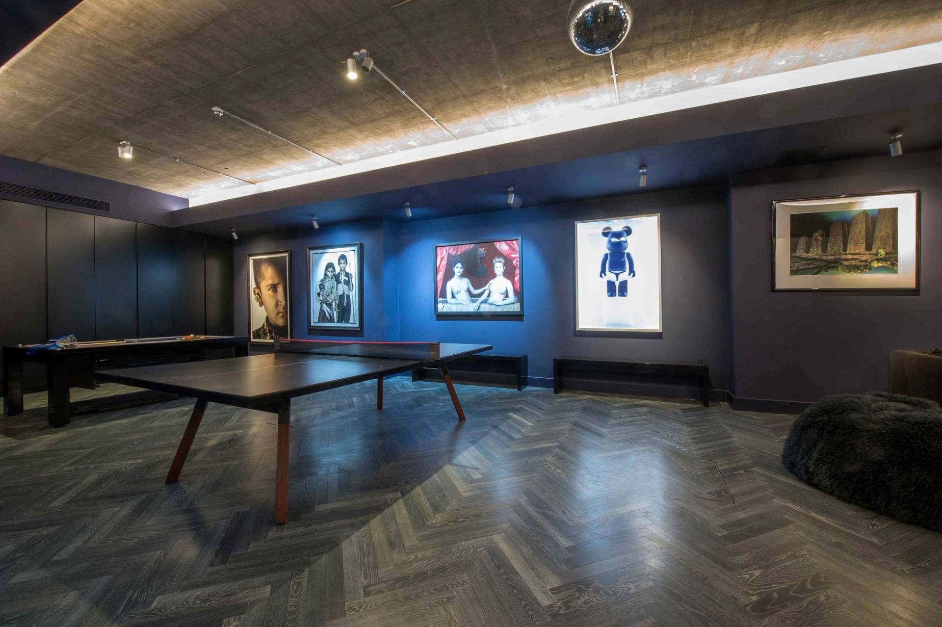 Spacious games room setup with a pool table, sleek flooring, and modern art pieces on dark feature walls, ideal for music videos, Love Locations.