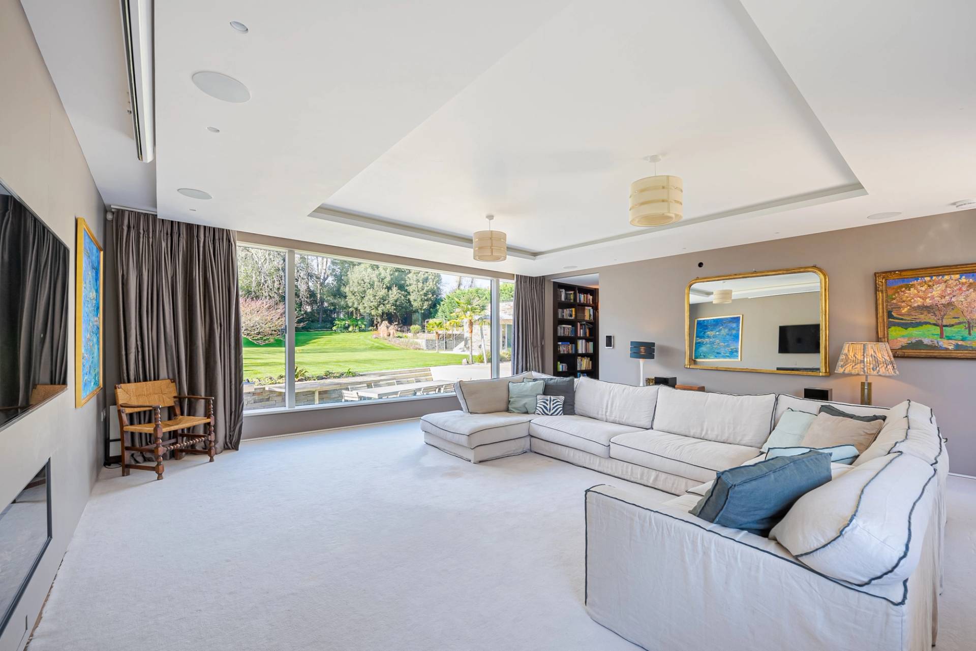 Spacious master bedroom lounge suite featuring white sofas, floor-to-ceiling garden view windows, and neutral carpet, Love Locations KT2.