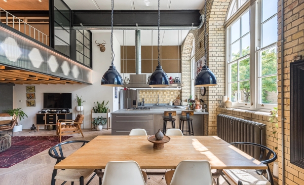pacious dining area with a long timber table and industrial pendant lights in a converted school conversion, Love Locations.