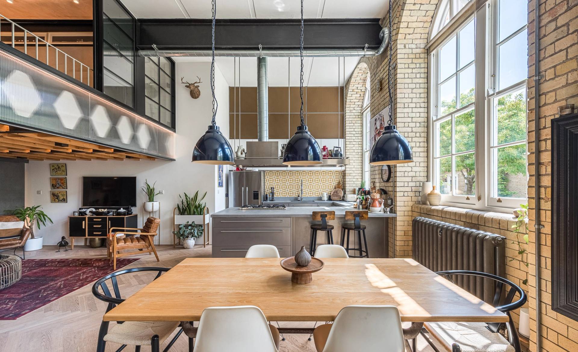 pacious dining area with a long timber table and industrial pendant lights in a converted school conversion, Love Locations.