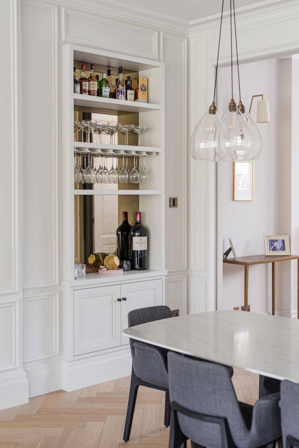 Built-in white alcove display cabinetry with glass shelving set in a dining room, Love Locations TW11.