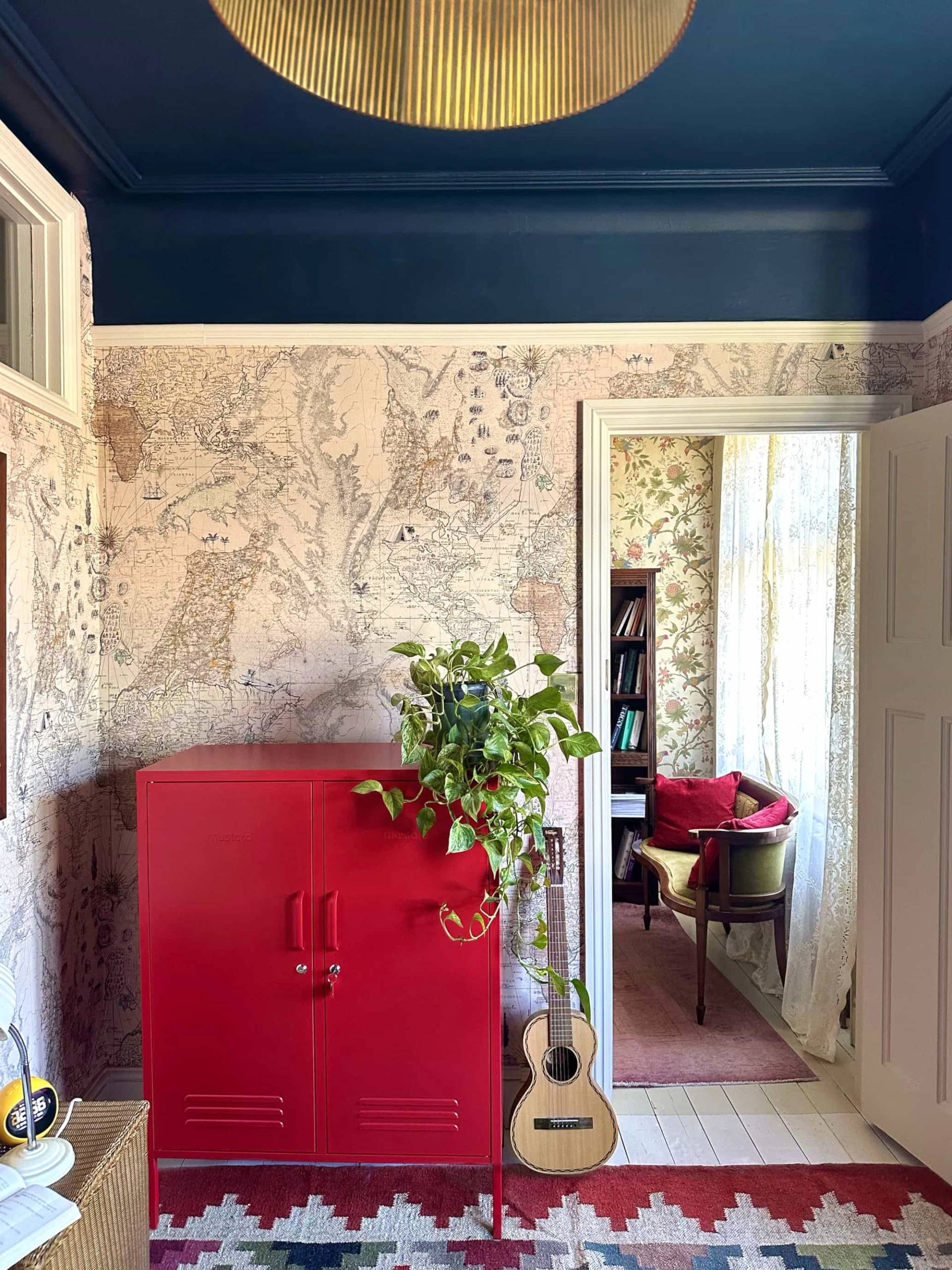 Colorful bedroom doorway view featuring a red cabinet, floral wallpaper, and blue ceiling, Love Locations N13.