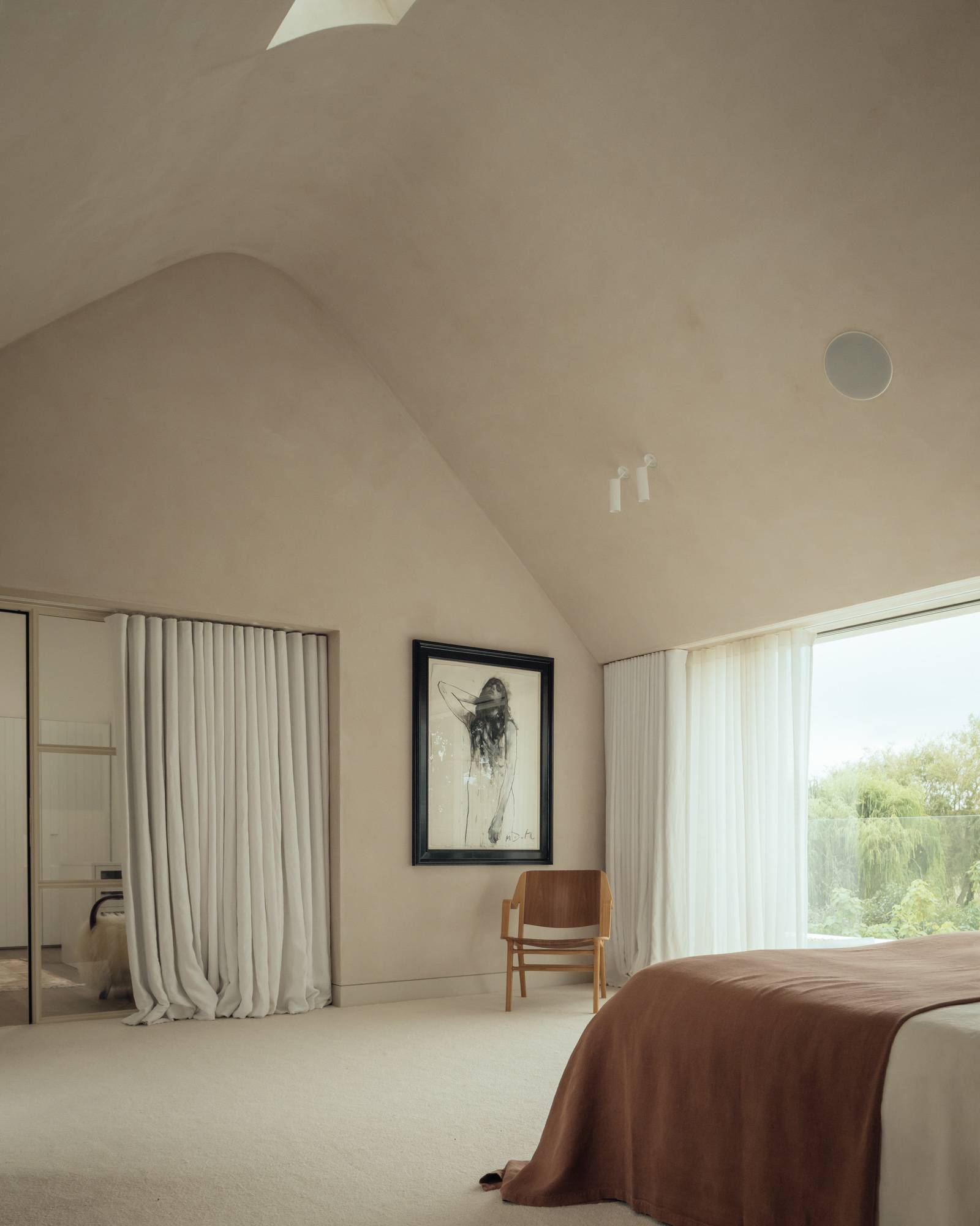 Vaulted master bedroom shoot location featuring curved plaster ceilings, rust linen bedding, and full-height windows, ideal for luxury mattress advertising via Love Locations.