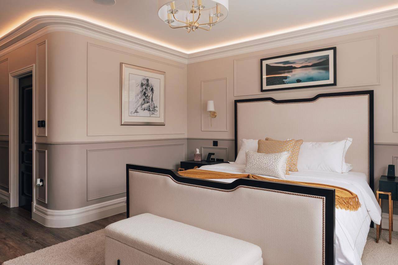 Luxury master bedroom suite featuring a black upholstered bed frame, gold accent throw, and ambient LED cove lighting, ideal for mattress and sleepwear brand campaigns, Love Locations.