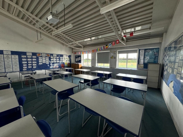 Love Locations institutional school classroom space EN4: Brightly lit academic classroom showing rows of student desks and chairs facing window bays, optimized for educational brand ads.