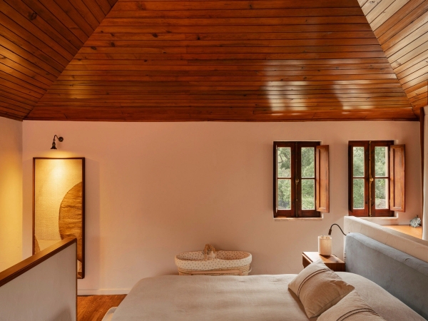 Serene bedroom layout with warm wood-clad ceiling, white bed, and soft ambient wall sconce light, Love Locations 2705-064.