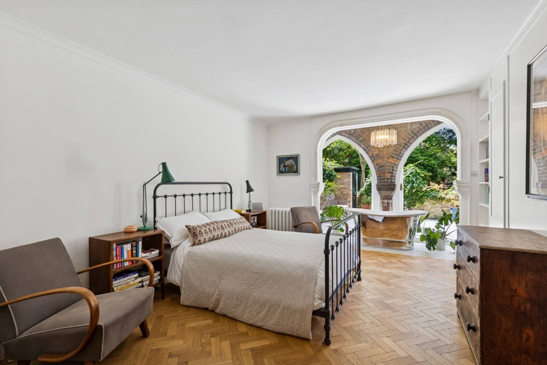 Bedroom location with parquet floors and arched opening into an ensuite bath area in Hampstead via Love Locations.