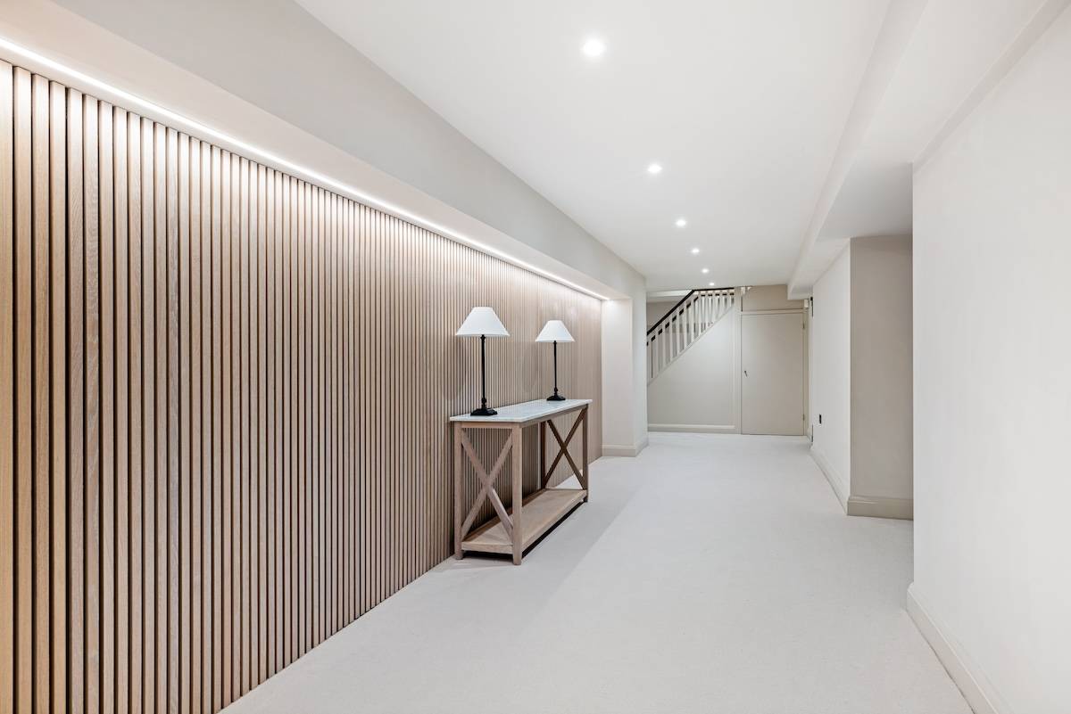 Basement corridor transition featuring vertical slatted wooden wall panelling and recessed strip lighting, Love Locations RH13.