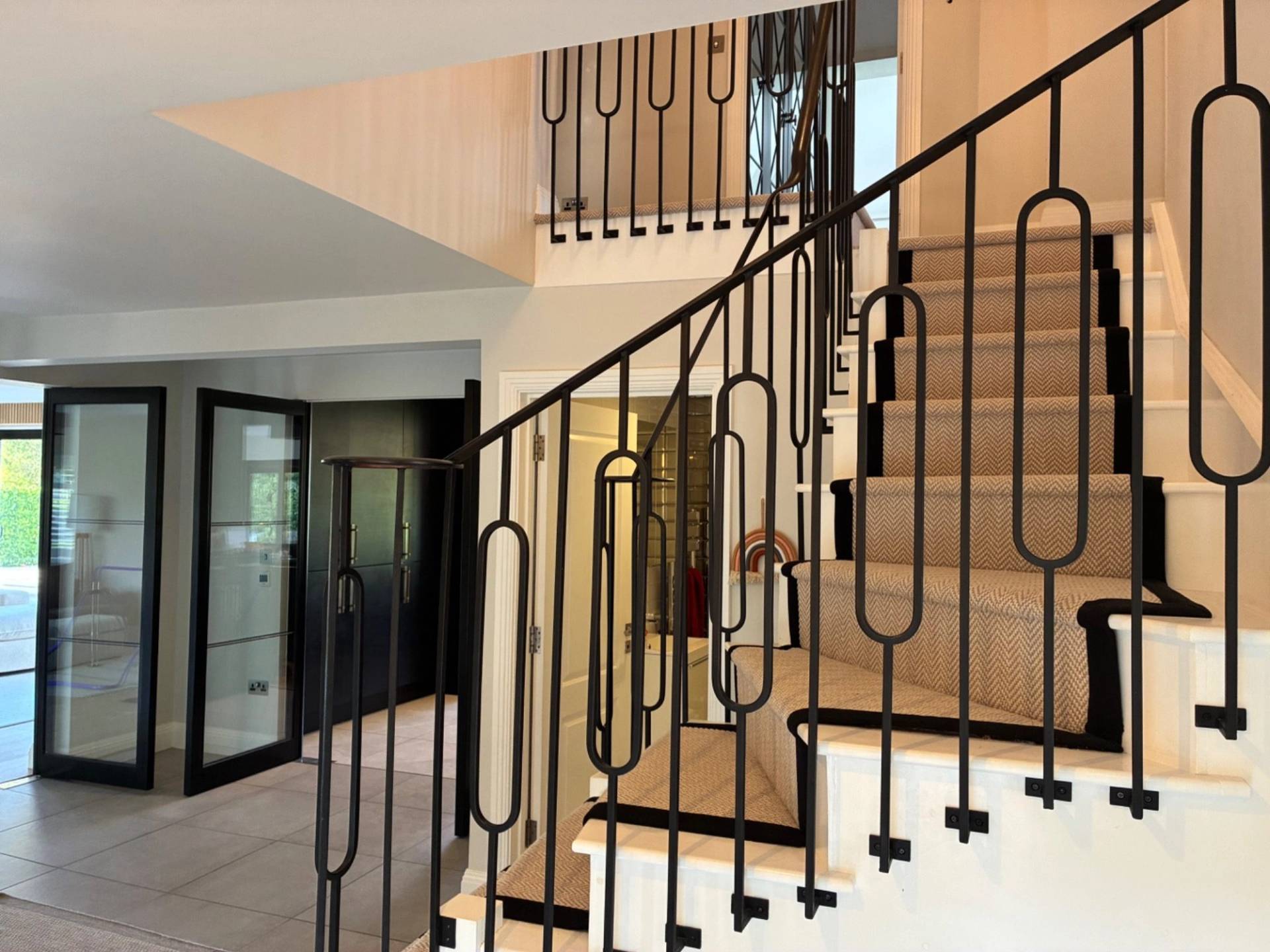Detailed close-up of a dramatic curved staircase and ornate black iron railings inside a luxury location house via Love Locations.