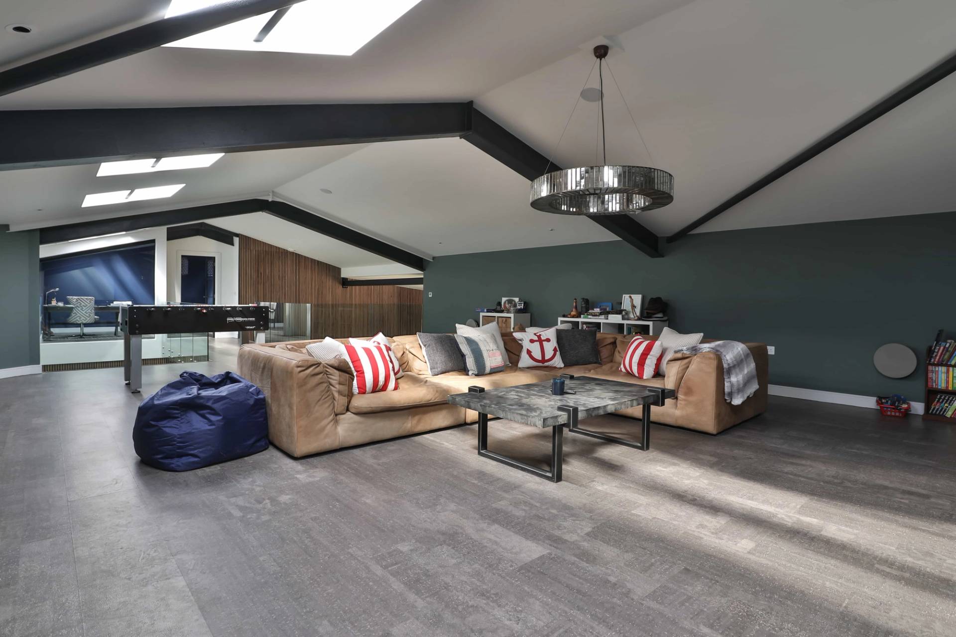Spacious mezzanine entertainment room with tan leather sofas, sloped ceilings, and skylights, Love Locations CV23.