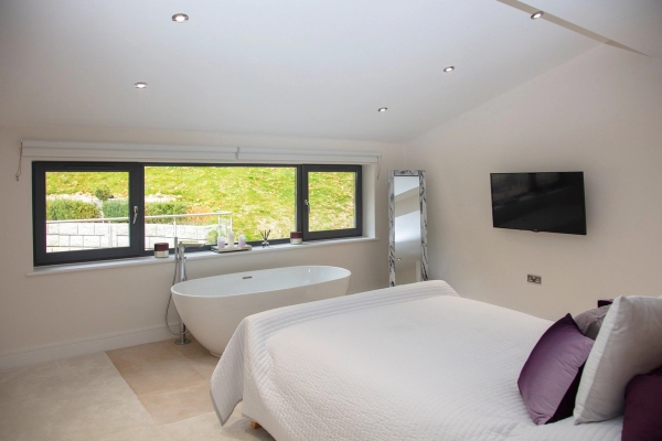 Alternate view of a high-end master bedroom suite looking toward tree-lined window views, ideal for luxury mattress brand shoots, Love Locations.