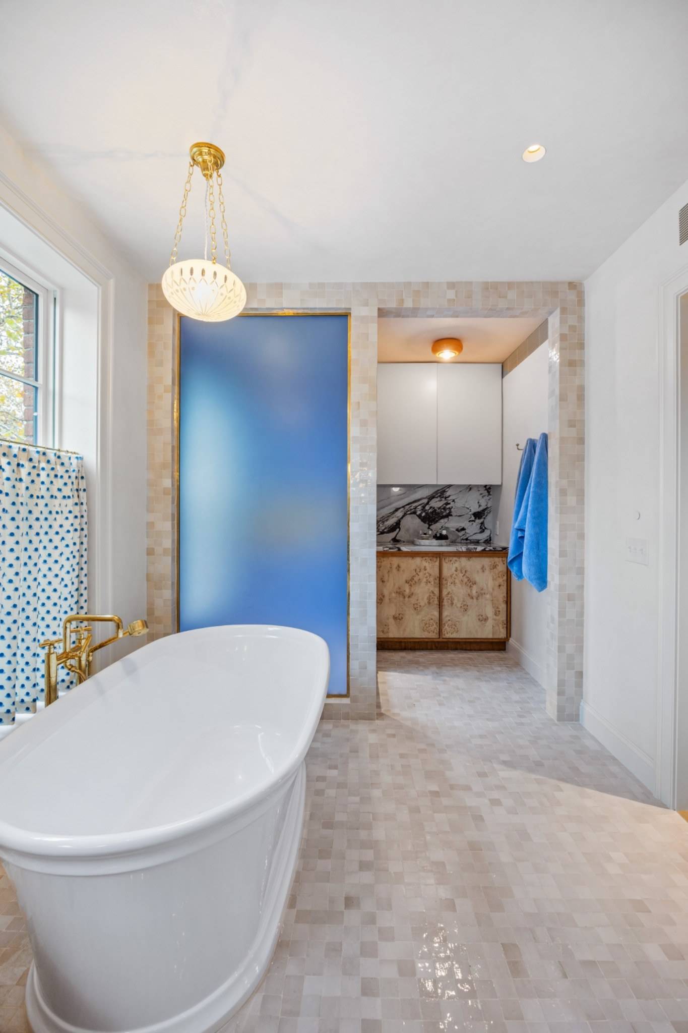 Luxurious master bathroom location in Boerum Hill Brooklyn NY 11217 through Love Locations, featuring a freestanding oval tub, blue frosted glass partition, and brass fixtures.