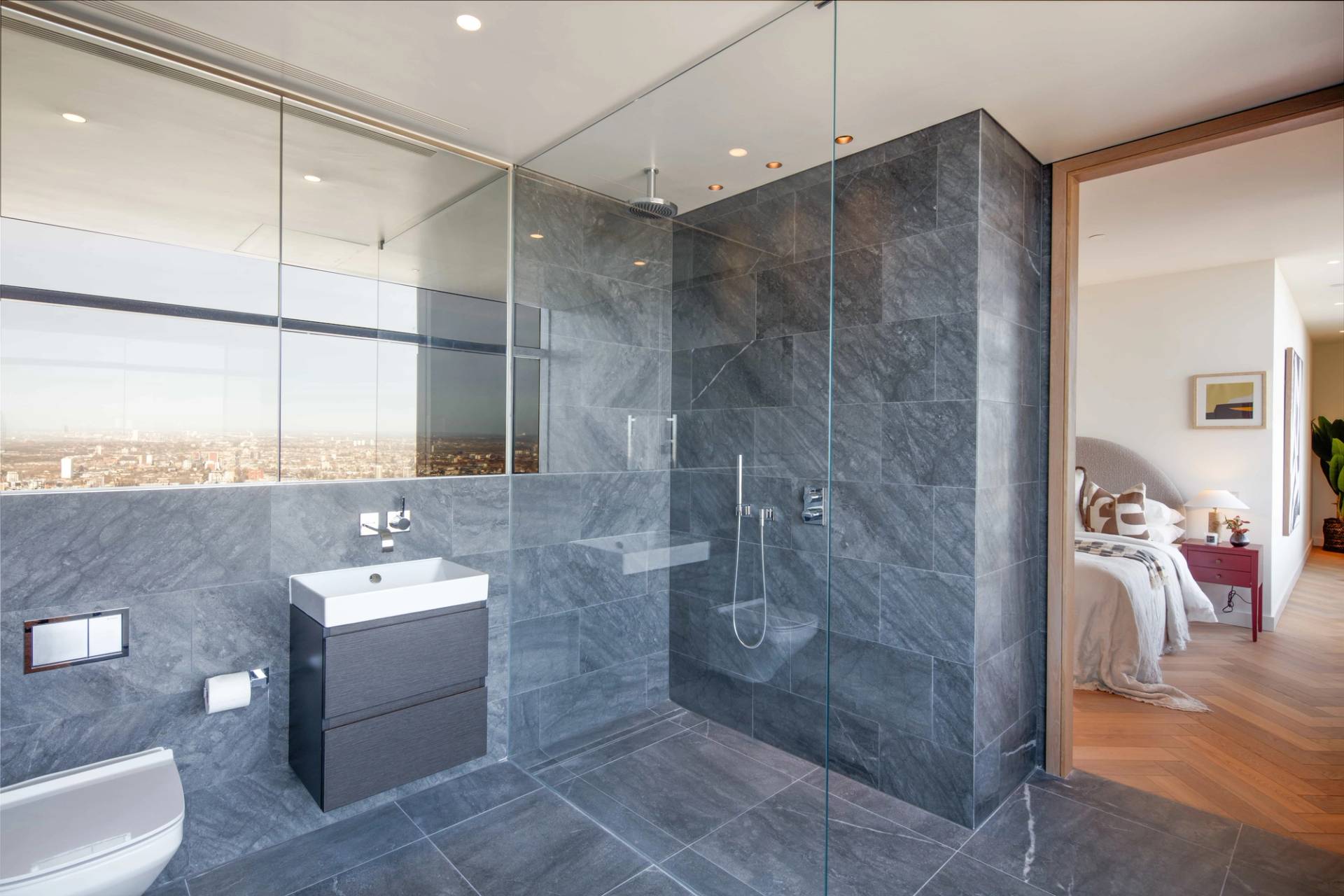 Modern walk-in glass shower room lined with grey stone tiles and frameless glass partitions, ideal for grooming product marketing, Love Locations.