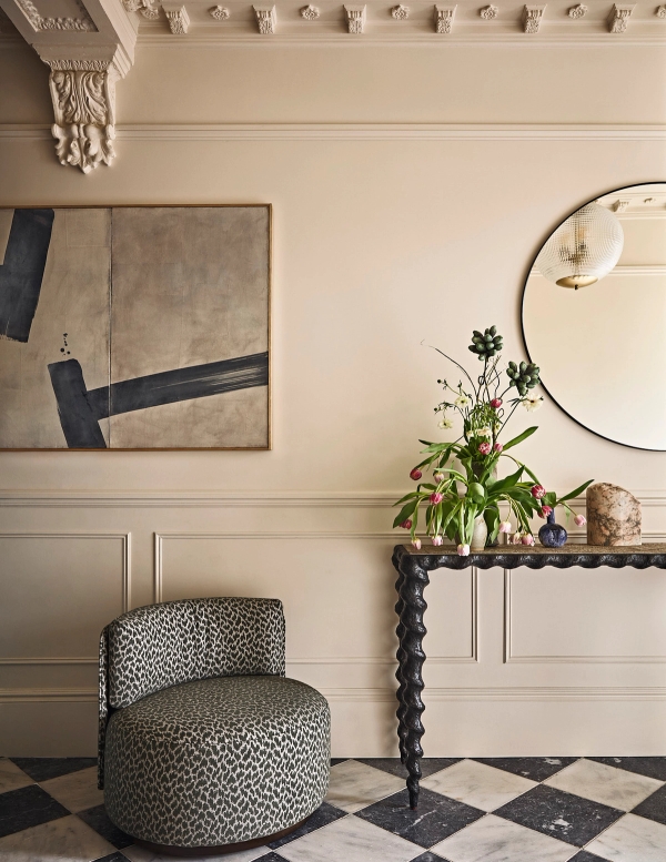 Neutral living room seating corner with grey patterned armchair, dark console table, and round wall mirror, Love Locations SE21.