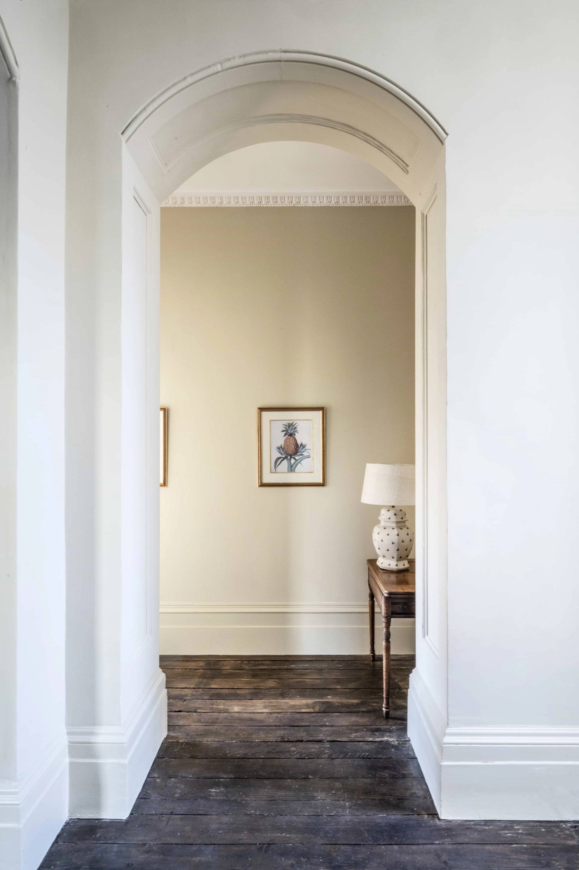 Clean neutral archway passage with dark polished timber floorboards, Love Locations.
