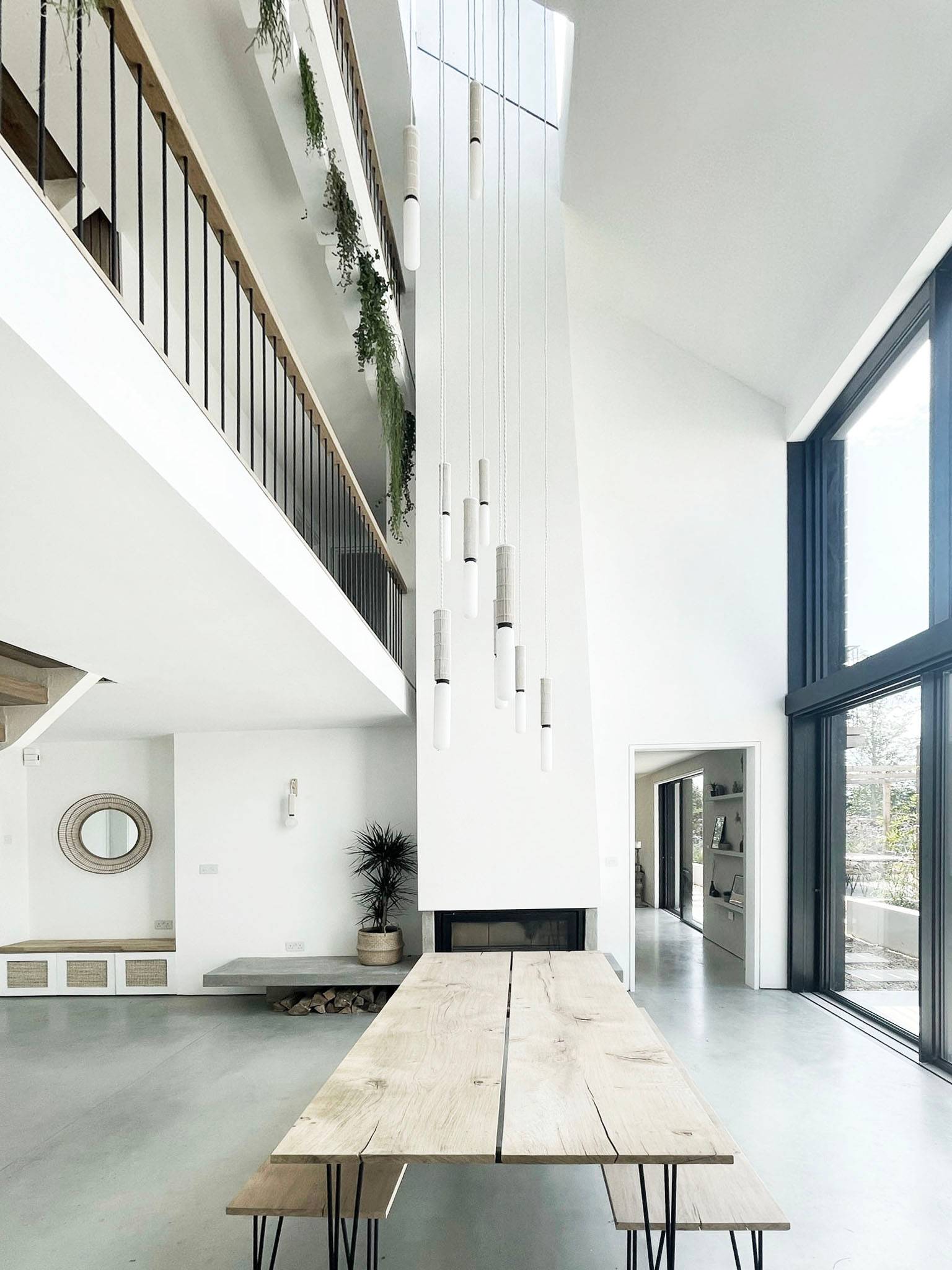 Double-height reception hall with a suspended modern fireplace, high-level glass windows, and floating dining table, perfect for high-end automotive and luxury brand ads, Love Locations.