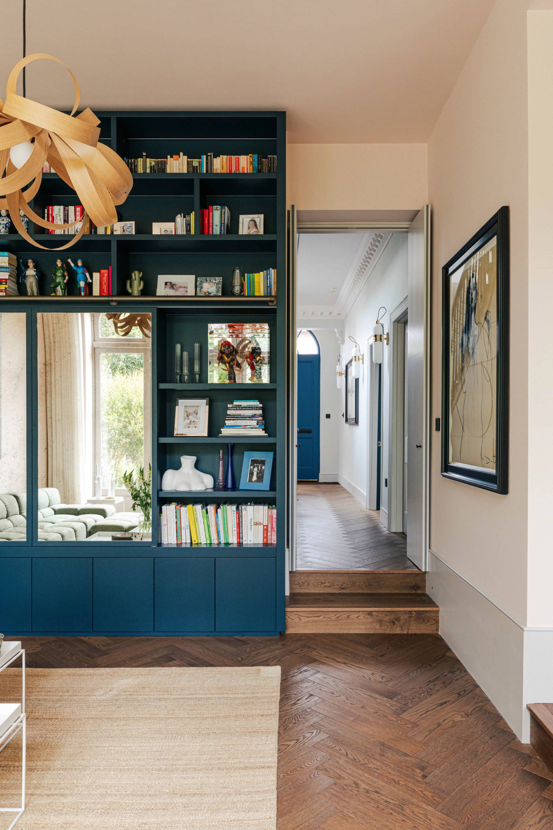 Corridor view looking past floor-to-ceiling blue bookcases into an entrance hallway, Love Locations SW13.