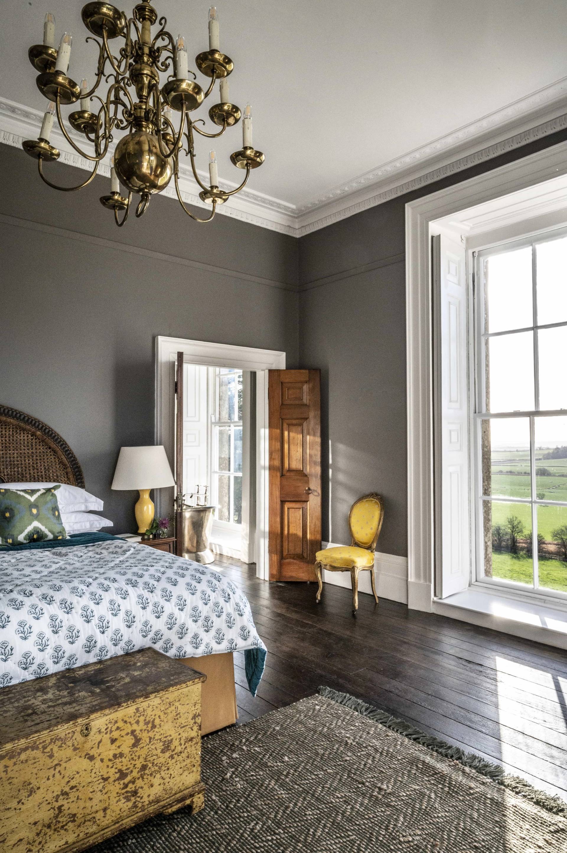 Charcoal grey bedroom suite displaying rich wood shutters and gold accent seating, Love Locations.